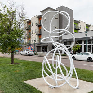 Twisted white metal sculpture sits in green grassy median