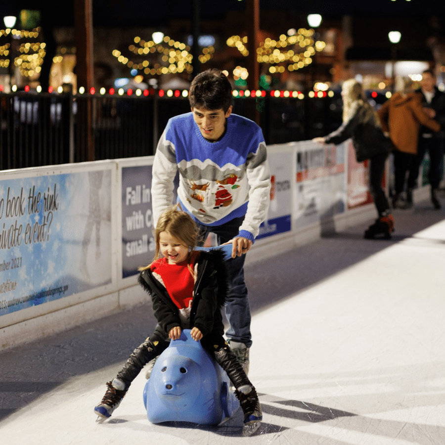 Man teaches child to ice skate.